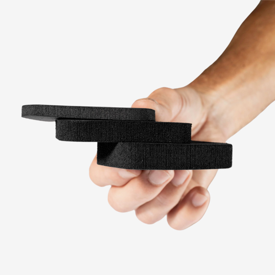 Hand holding 3 different pad sizes for the minimalist hernia belt